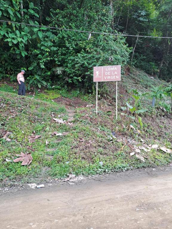 a man standing next to a sign on the side of a road at Alojamiento in Bahía Solano