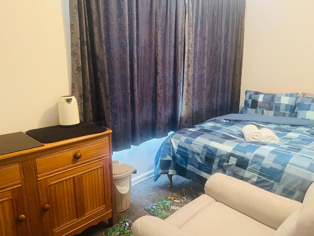 a bedroom with a bed and a chair and a dresser at Double bed room in Invercagill/5mini walk to city in Invercargill