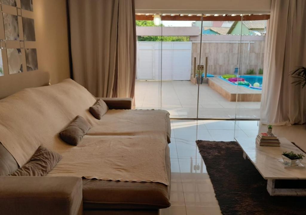 a living room with a couch and a swimming pool at Casa Espetacular Com Piscina in Cabo Frio