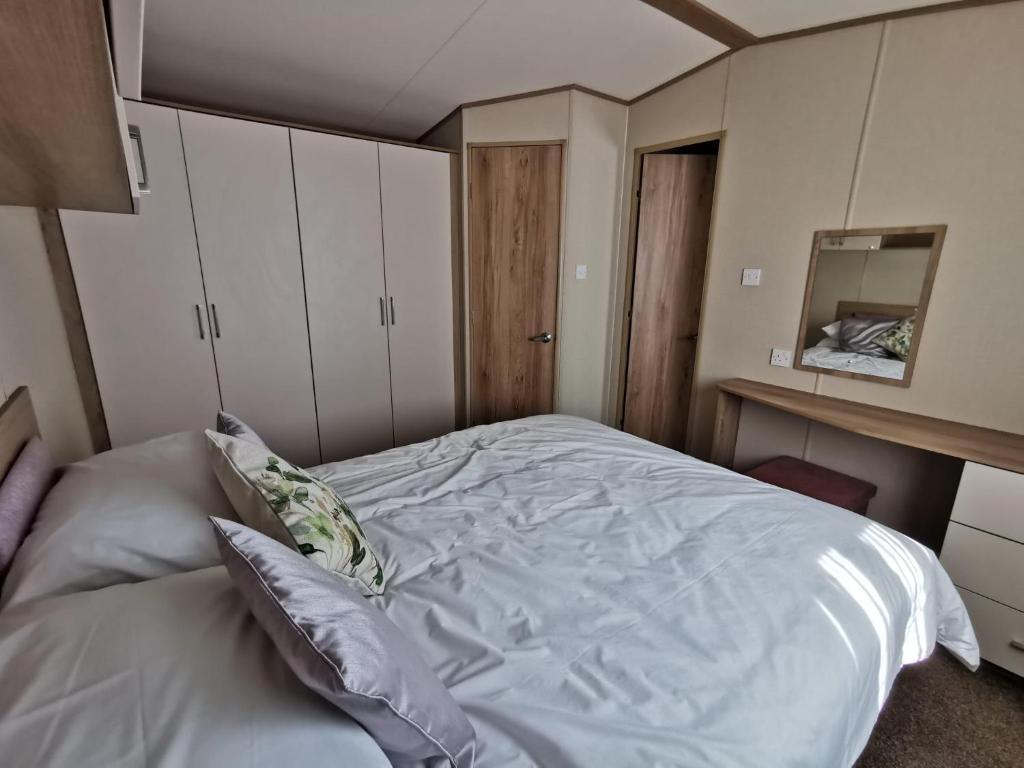 1 dormitorio con cama blanca y espejo en Lovely Caravan With Decking At Solent Breeze In Hampshire Ref 38195sb en Warsash