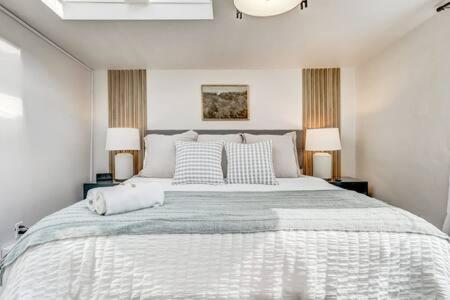 a white bedroom with a large bed with two lamps at Sandstone Suite King Kitchen SmartTVs WD & FirePIt in Colorado Springs