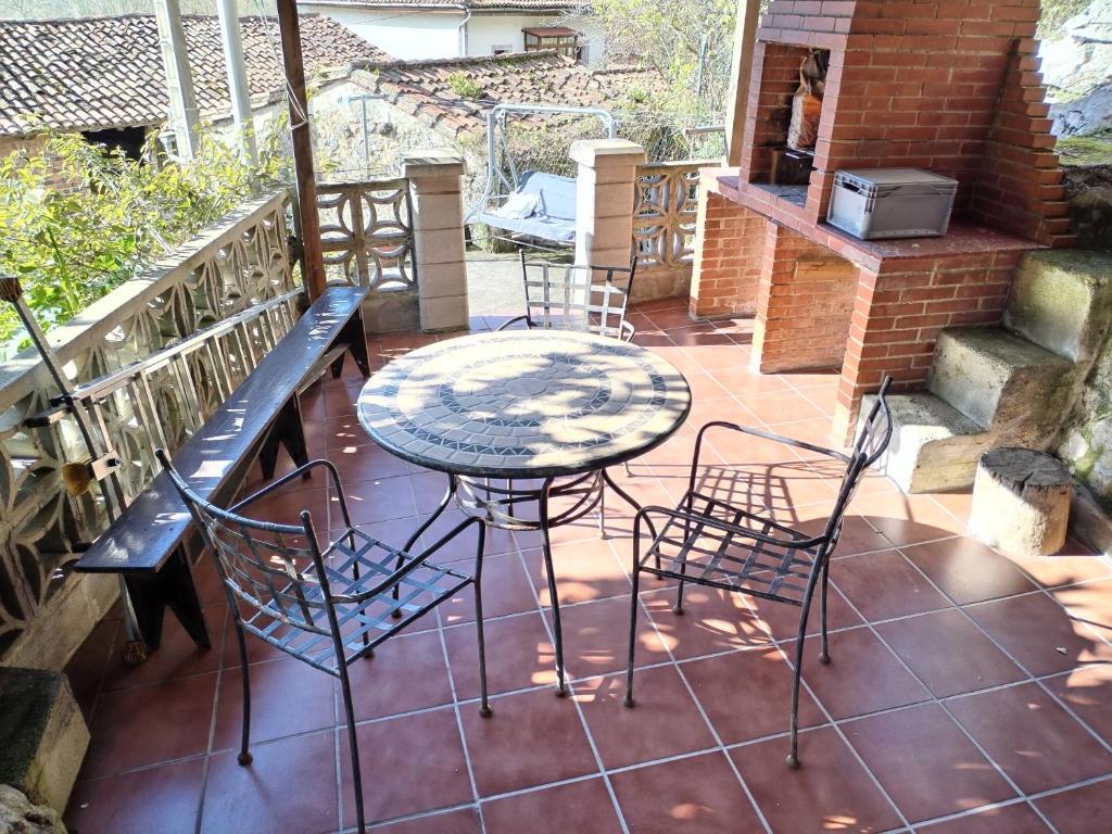 een patio met een tafel en stoelen en een grill bij Casa Molily in Llanes
