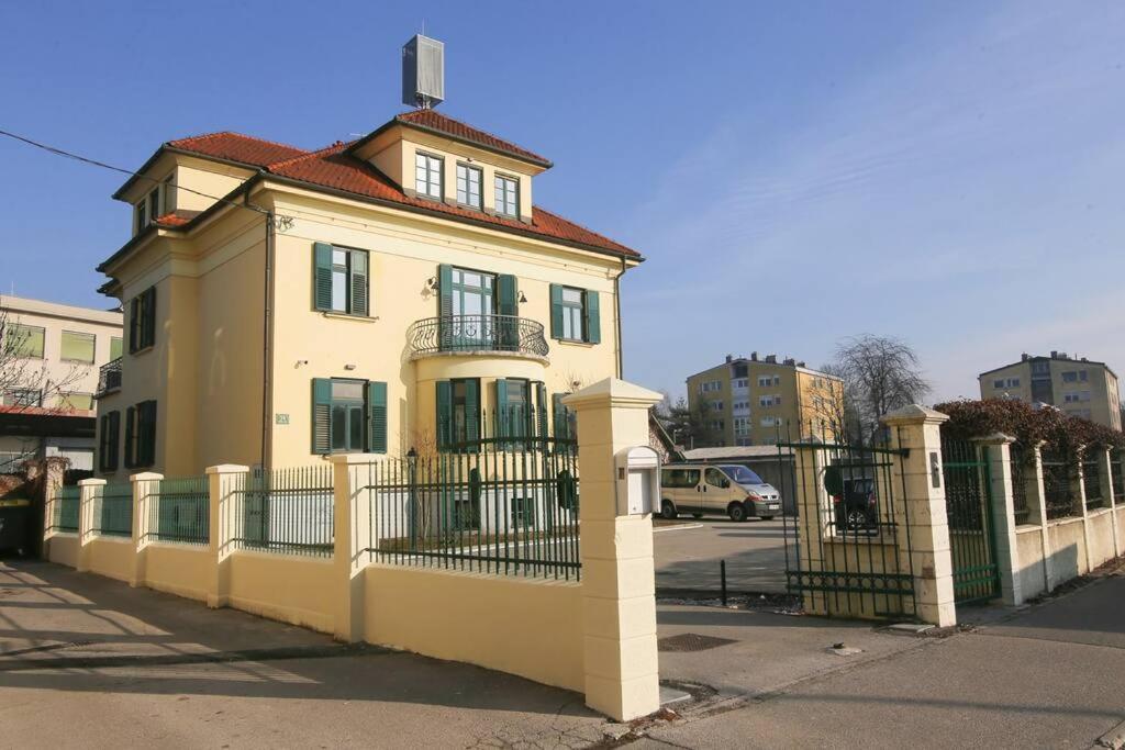 a yellow house with a fence in front of it at Budget dbl Studio free breakfast in Ljubljana