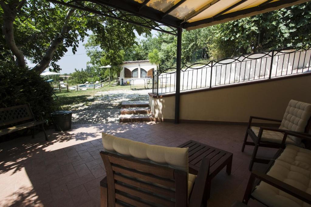 un patio con sillas, una mesa y una valla en B&B Cà Biocco en Sogliano al Rubicone