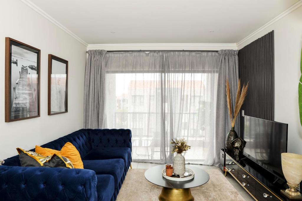 sala de estar con sofá azul y TV en Eirini Elegant - Athena Apartment Fourways, en Sandton