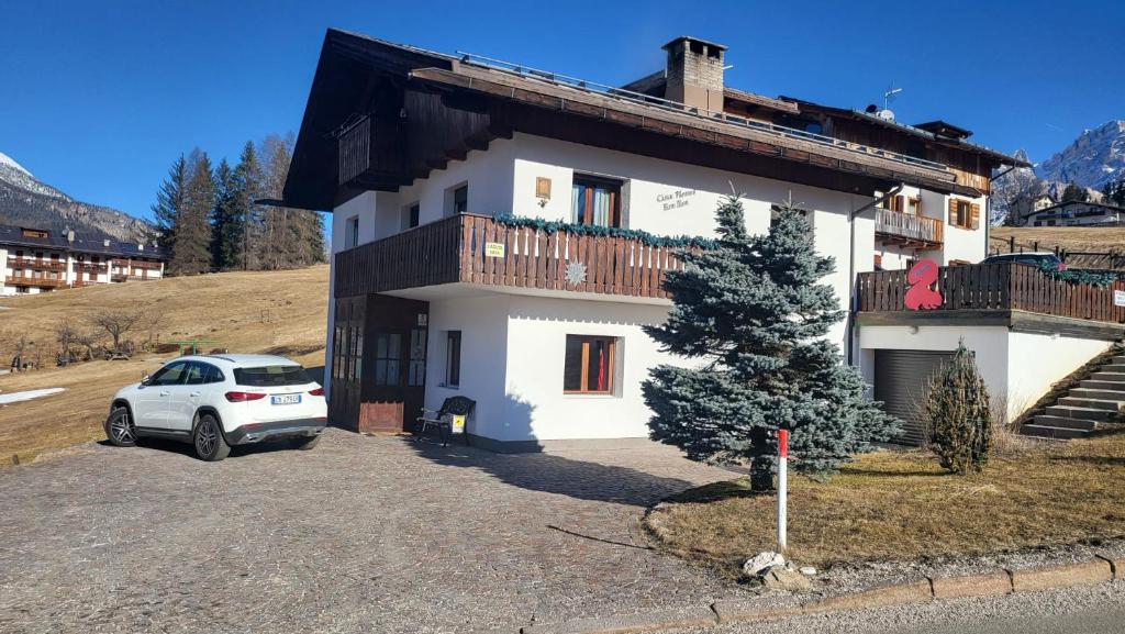 una casa bianca con una macchina parcheggiata di fronte di Affittacamere Iragidor a Cortina dʼAmpezzo