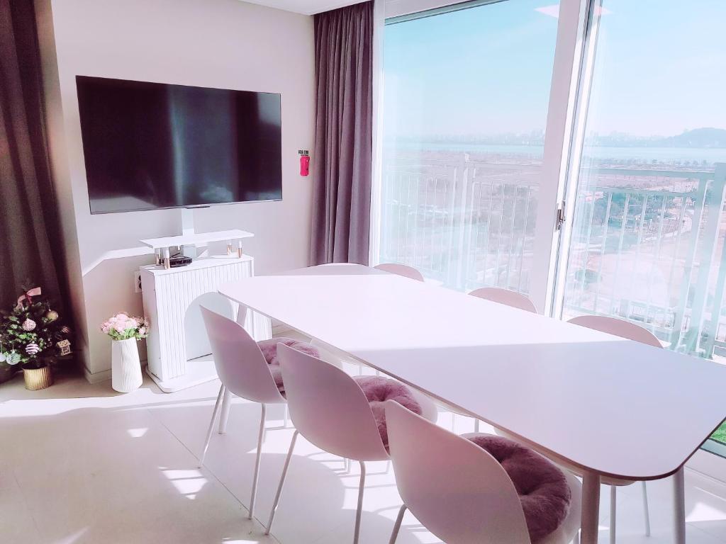 una sala de reuniones con mesa, sillas y una gran ventana en Lovely House en Incheon