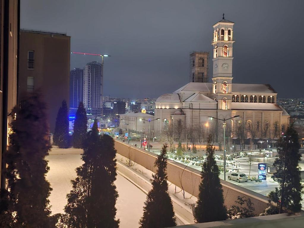un grand bâtiment avec une tour d'horloge dans une ville dans l'établissement Prishtina Central Apartment, à Pristina