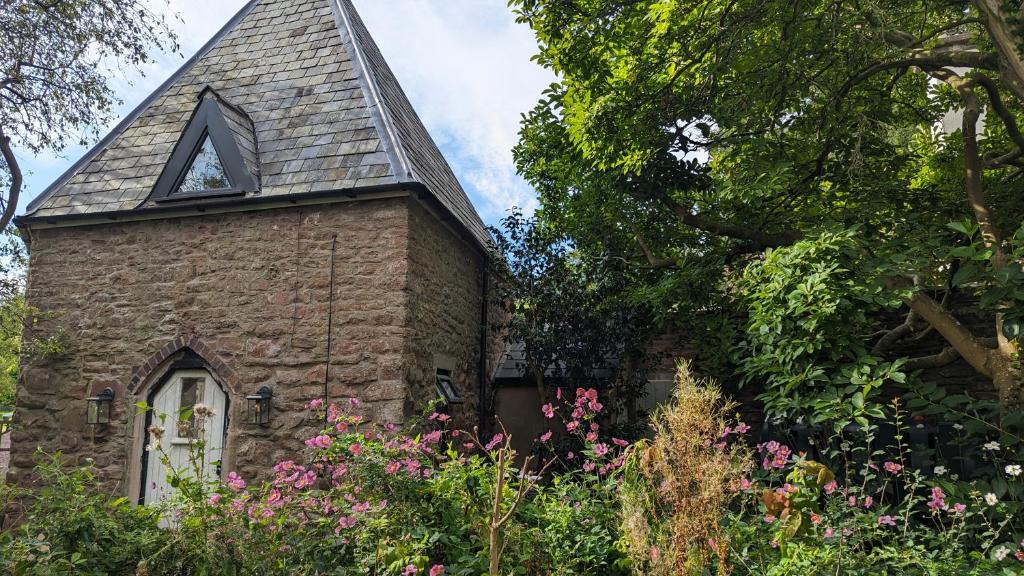 an old stone church with a triangular window and flowers at Fairy Cottage in Lea