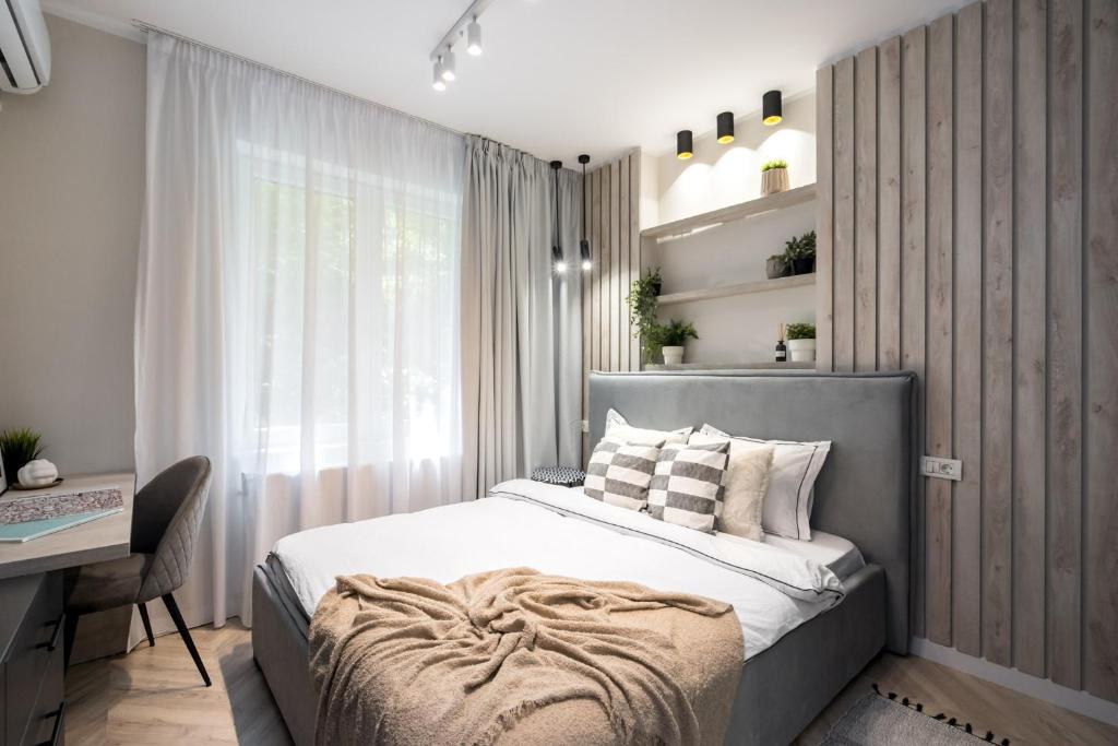 a bedroom with a bed and a desk and a window at POWELI City Center in Bucharest