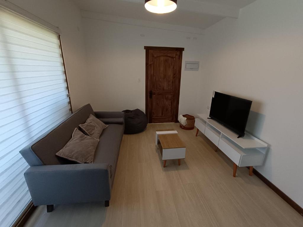 ein Wohnzimmer mit einem Sofa und einem Flachbild-TV in der Unterkunft Refugio las Quemas in Futrono