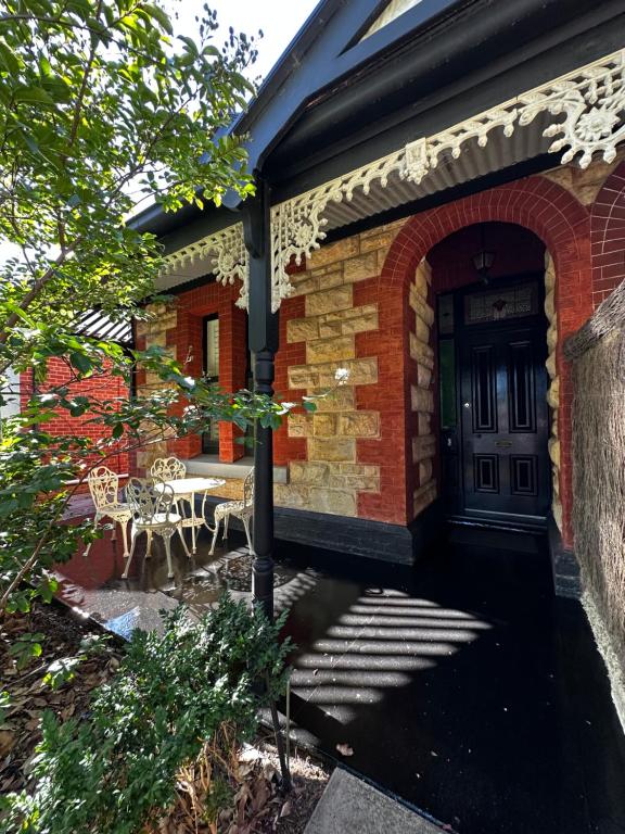 a brick house with a door and a table and chairs at HAVEN: Stunning Unley *history*location*charm 3bd in Unley
