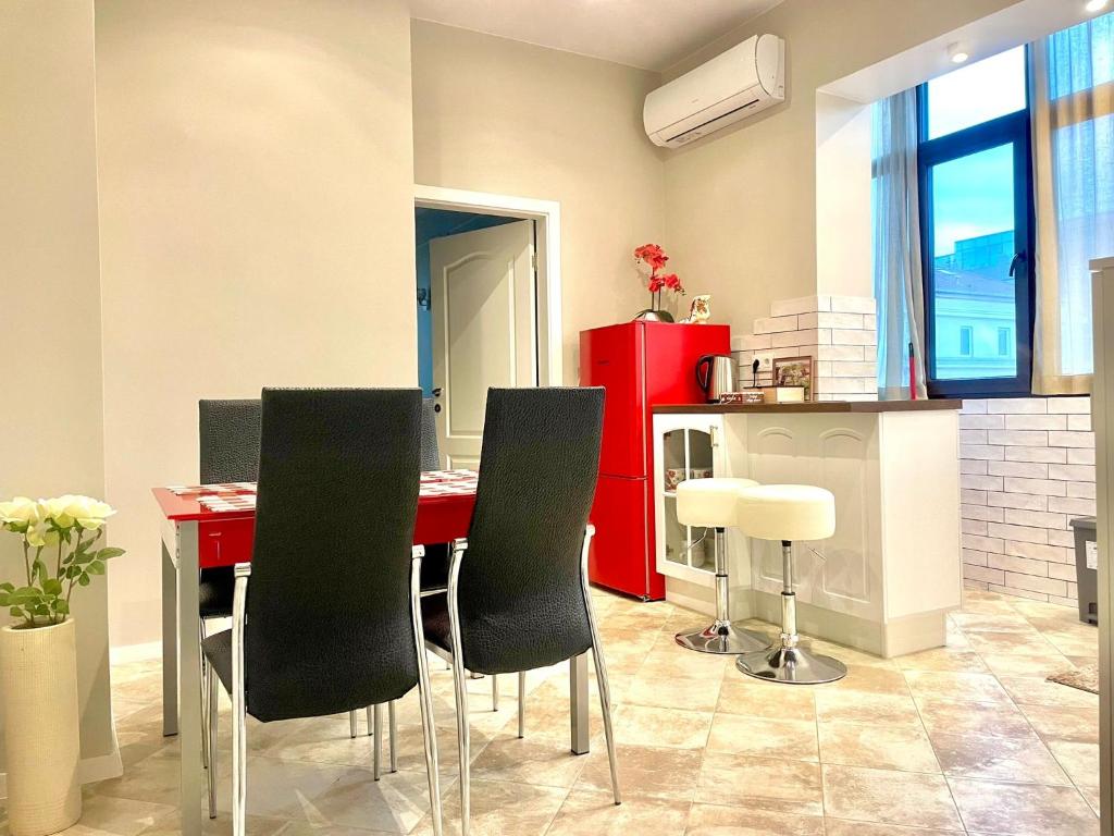 a kitchen with a red table and black chairs at Nataly New luxury apartment on Black sea in Varna City