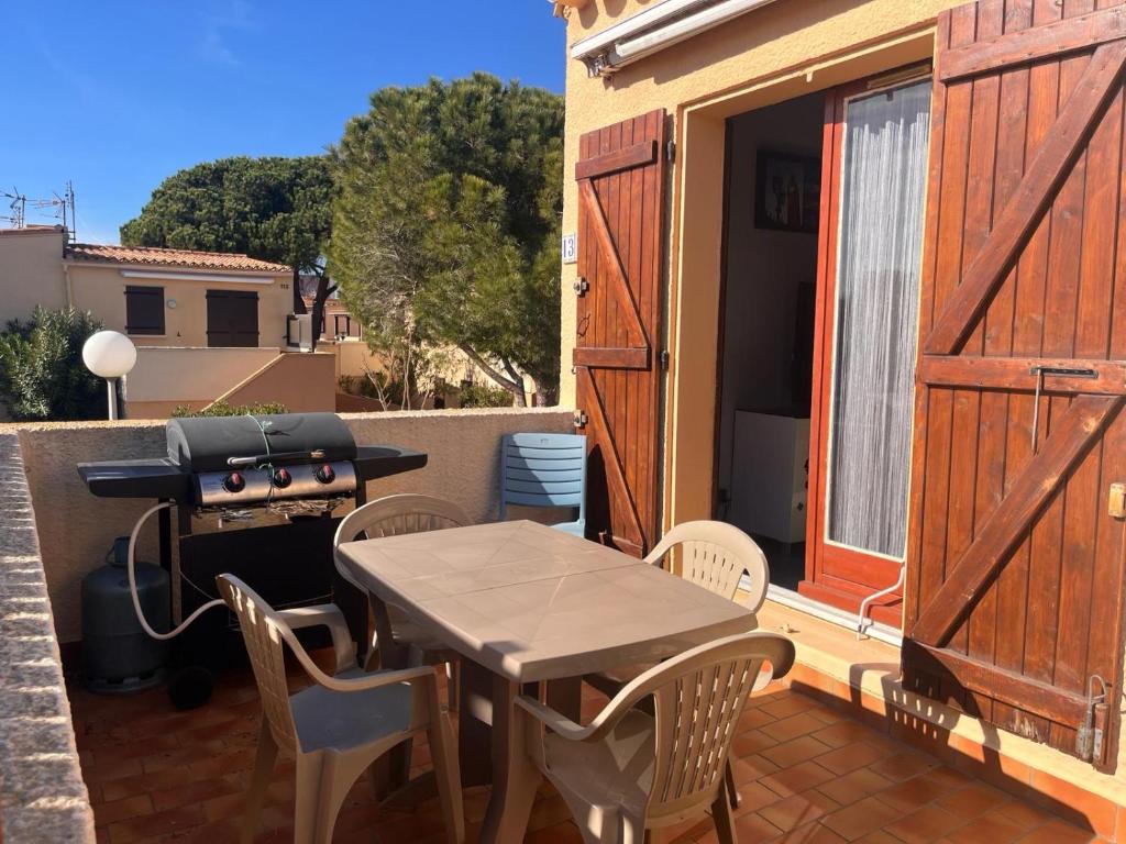 un patio avec une table, des chaises et un barbecue dans l'établissement Appartement 4 pers Port Leucate résidence Les Sablons 3, à Leucate