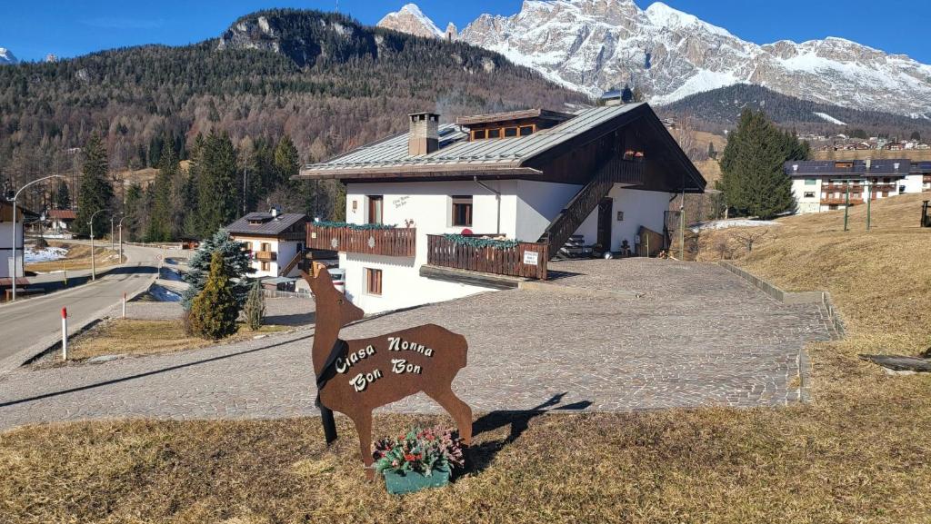 un cartello di fronte a una casa con una montagna di Ciasa Nonna Bon Bon a Cortina dʼAmpezzo
