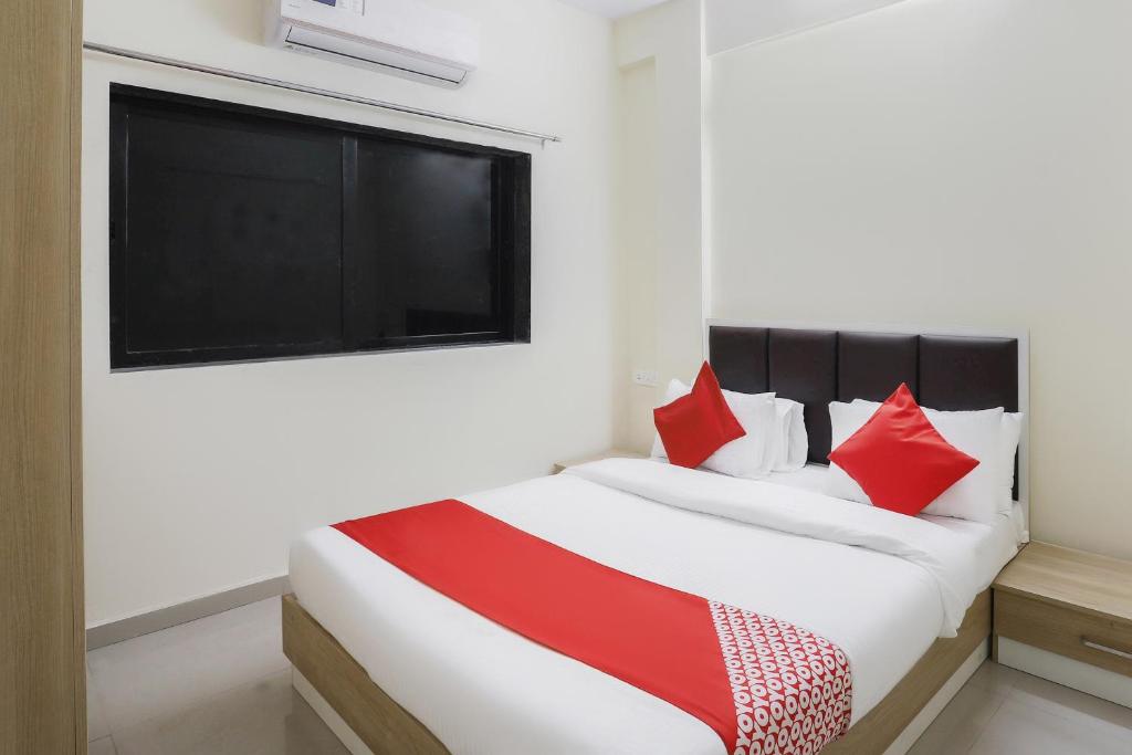 Schlafzimmer mit einem Bett mit roten Kissen und einem Fenster in der Unterkunft OYO Zion Inn in Vapi