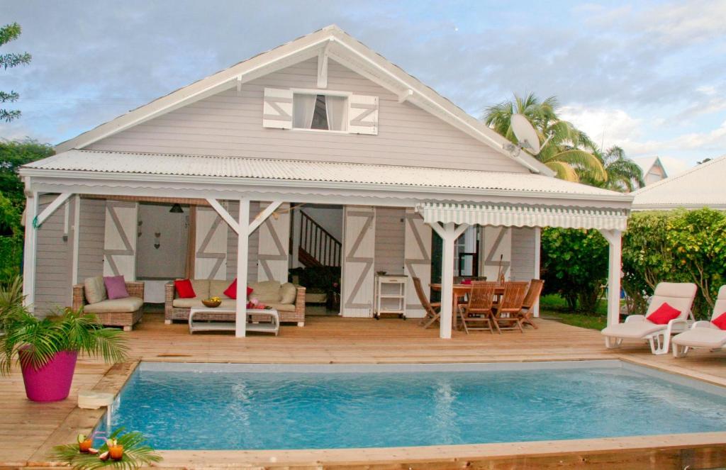 een huis met een zwembad ervoor bij La Petite Villa Guadeloupe in Sainte-Anne