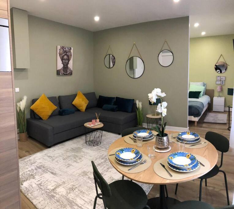 un salon avec une table et un canapé dans l'établissement LÉchappée Belle Métro 9 WiFi-Clim-NETFLIX, à Montreuil