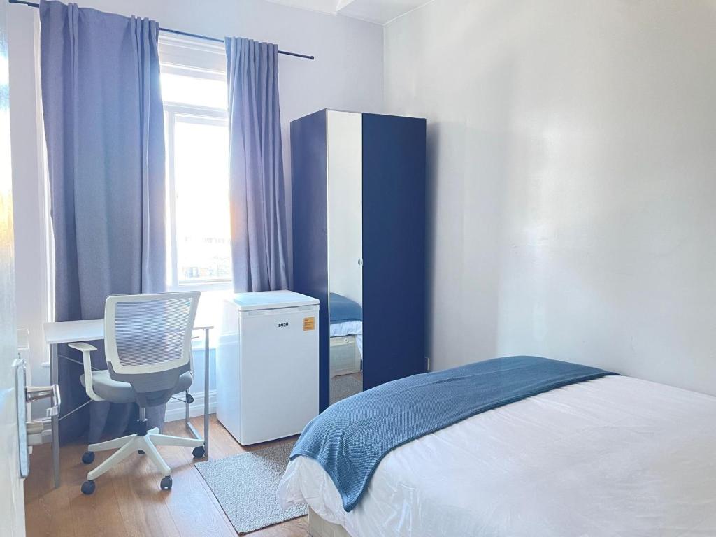 um quarto com uma cama, uma secretária e uma cadeira em Dalston's Rooms em Londres