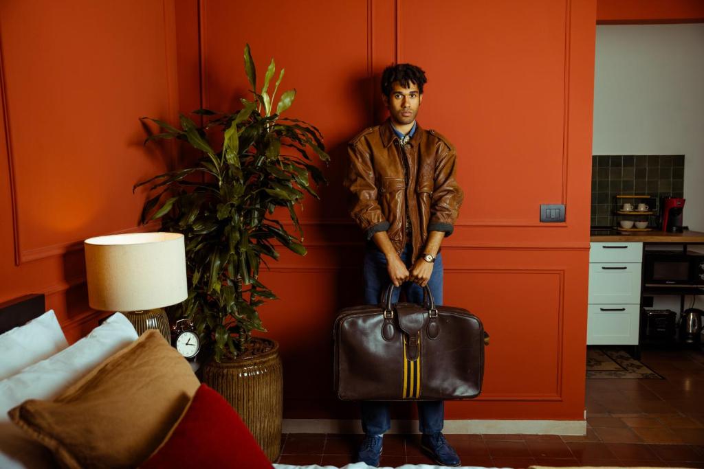 Ein Mann, der eine braune Tasche in einem Zimmer hält. in der Unterkunft Kondo Maisons in Catania