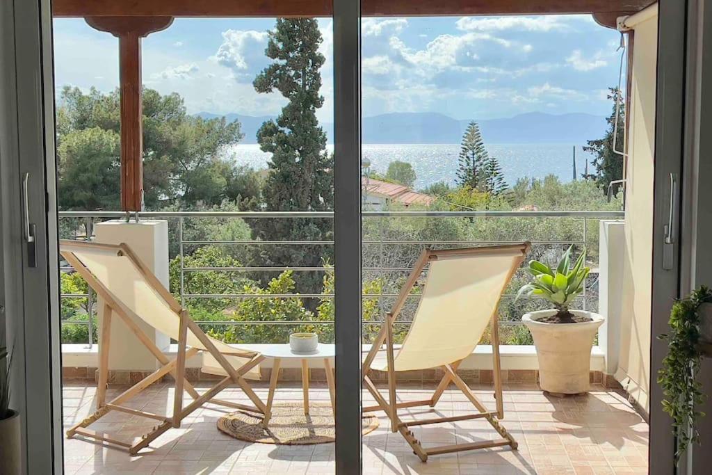 two chairs and a table on a balcony with a view at Villa Oinoni in Egina