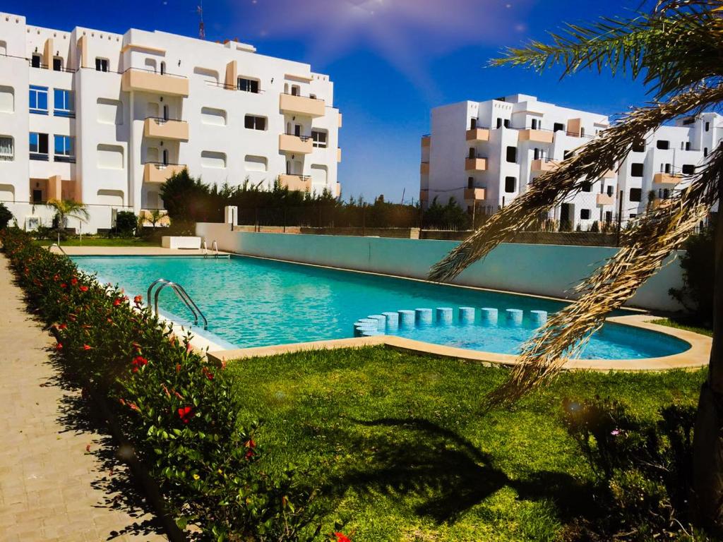 uma piscina em frente a alguns edifícios de apartamentos em Fantastique Appartement avec piscine sur la plage M2 em Tânger
