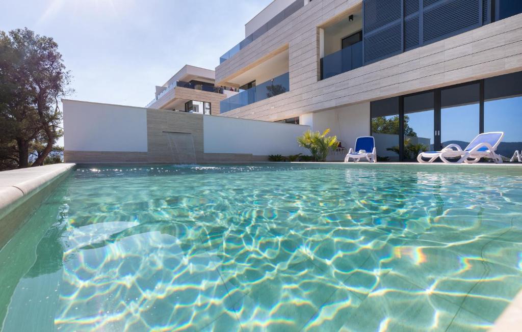 a swimming pool with two chairs in front of a building at Villa Delux View in Komarna