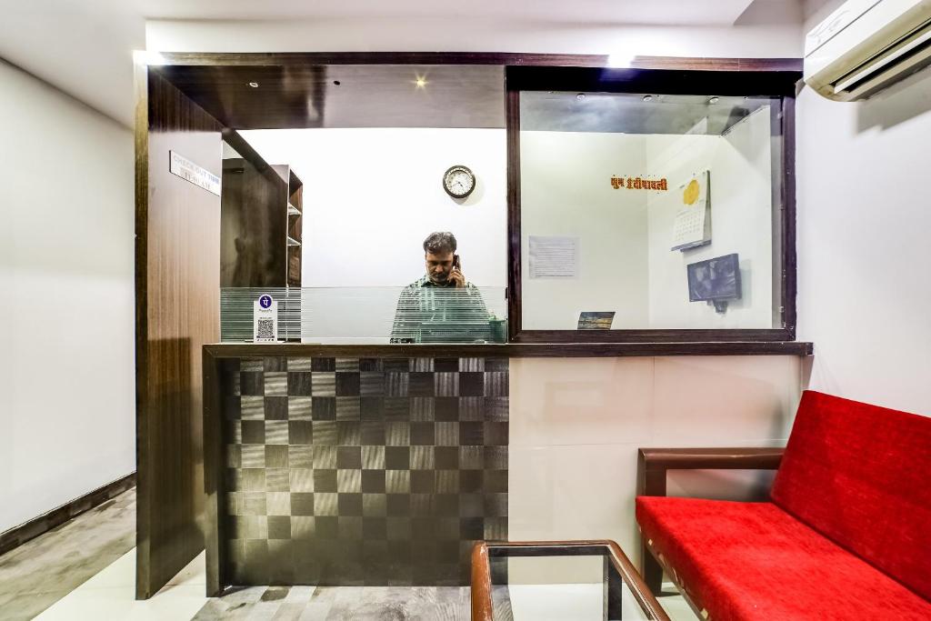 a man in a mirror in a room with a red couch at OYO 66982 Hotel Skyway Inn in Mumbai