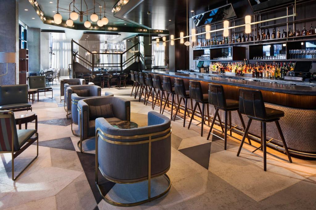 a bar with a row of chairs in a restaurant at Thompson Nashville, by Hyatt in Nashville
