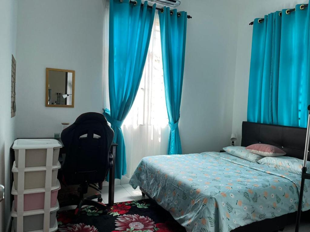 um quarto com cortinas azuis e uma cama e uma cadeira em Damai Kangar Homestay em Kangar