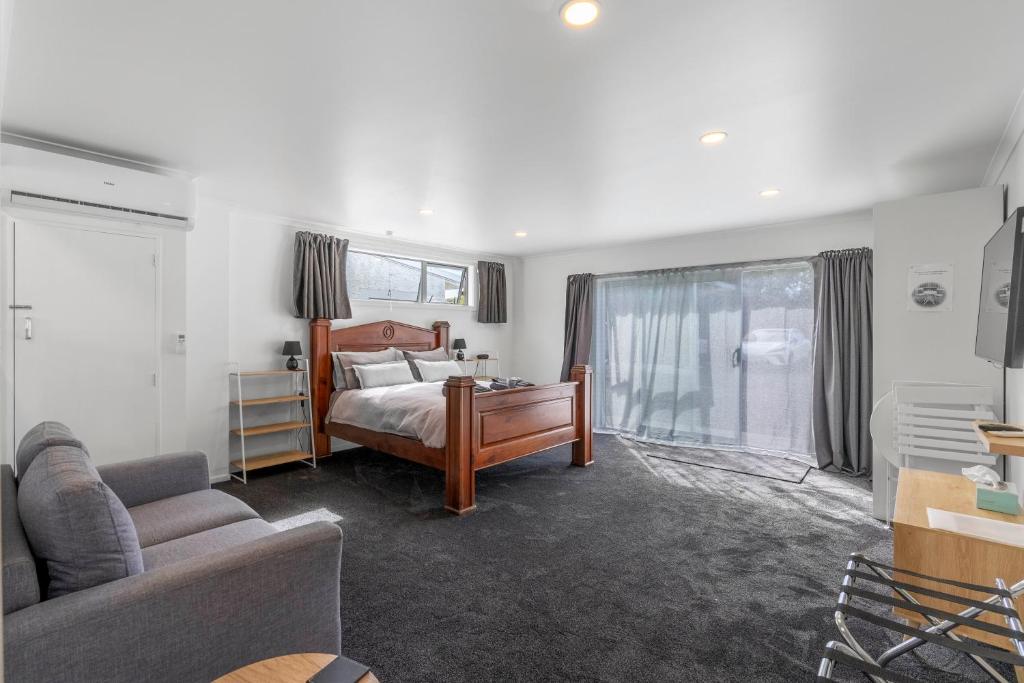 a bedroom with a bed and a living room with a couch at Nine Acres in Invercargill