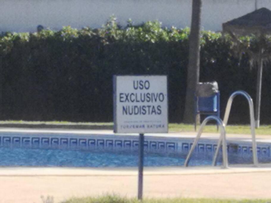 ein Schild neben einem Pool mit einem Benutzerschutzungsschild in der Unterkunft Torremar vera playa naturista in Vera