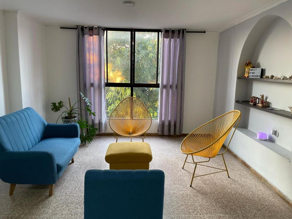 d'un salon avec un canapé bleu, des chaises et une fenêtre. dans l'établissement Sweet Home RIOHACHA, à Ríohacha