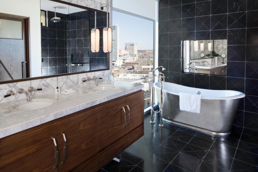 a bathroom with two sinks and a tub and a mirror at Thompson Nashville, by Hyatt in Nashville