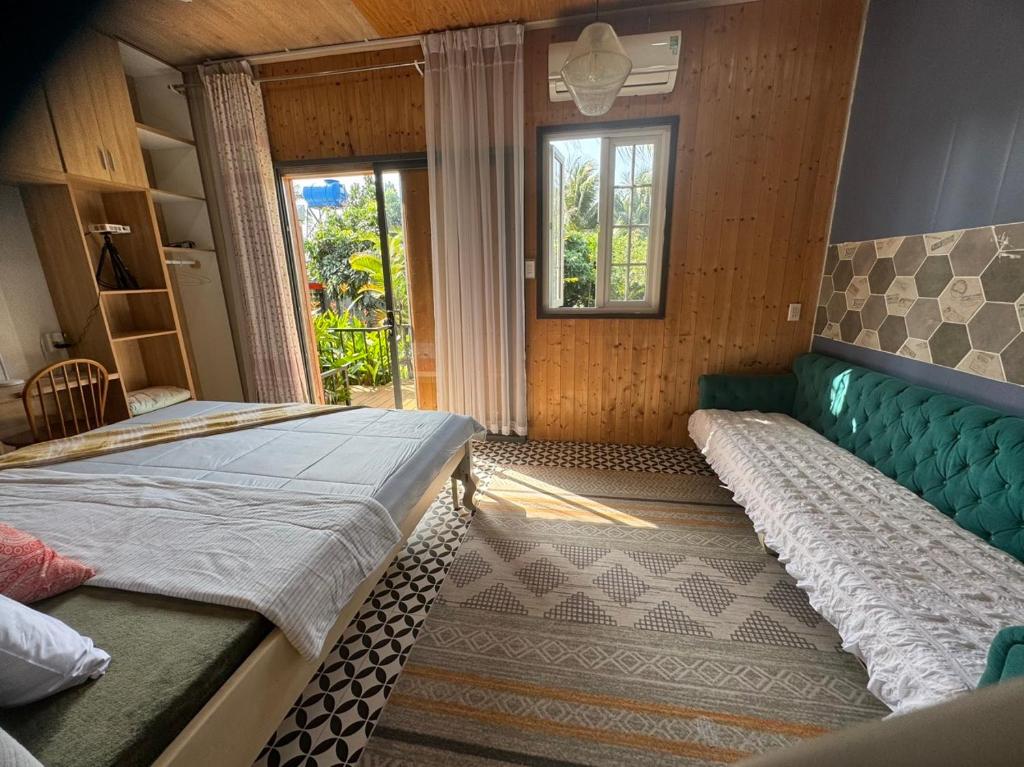 a bedroom with two beds and a couch and a window at Lọ Lem Homestay in Vĩnh Long