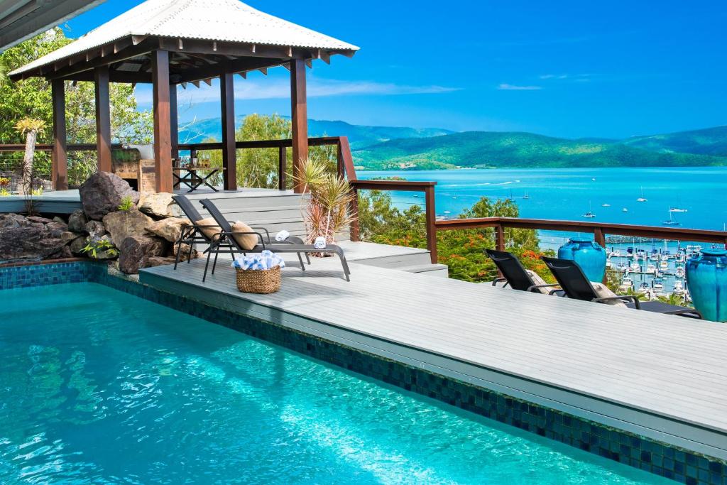 a swimming pool with chairs and a gazebo at Airlie Beach Seaviews in Airlie Beach