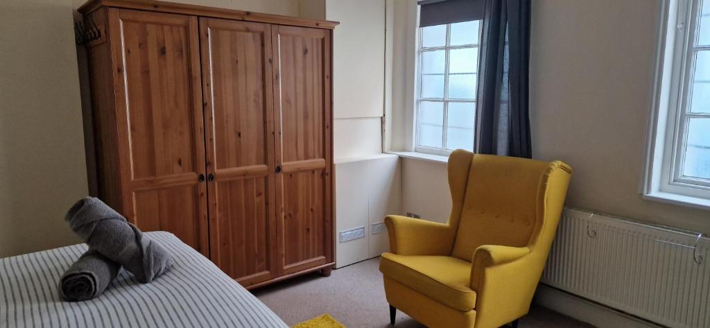 a bedroom with a bed and a yellow chair and a cabinet at The Copper fields in London