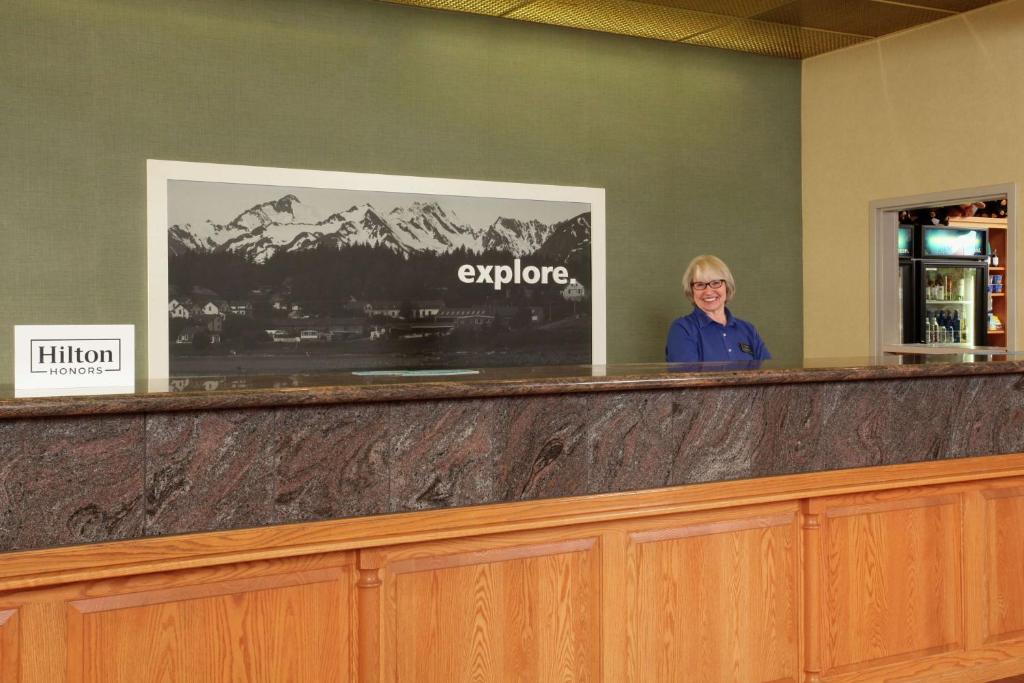 a woman standing at the reception counter of a hotel at Hampton Inn Kalispell in Kalispell