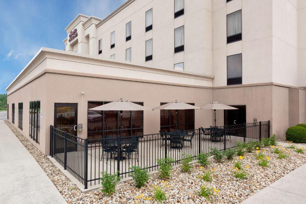 a building with tables and umbrellas in front of it at Hampton Inn & Suites Grove City in Grove City