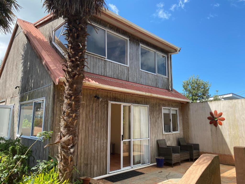 a house with a palm tree in front of it at Oneroa Chalet in Oneroa