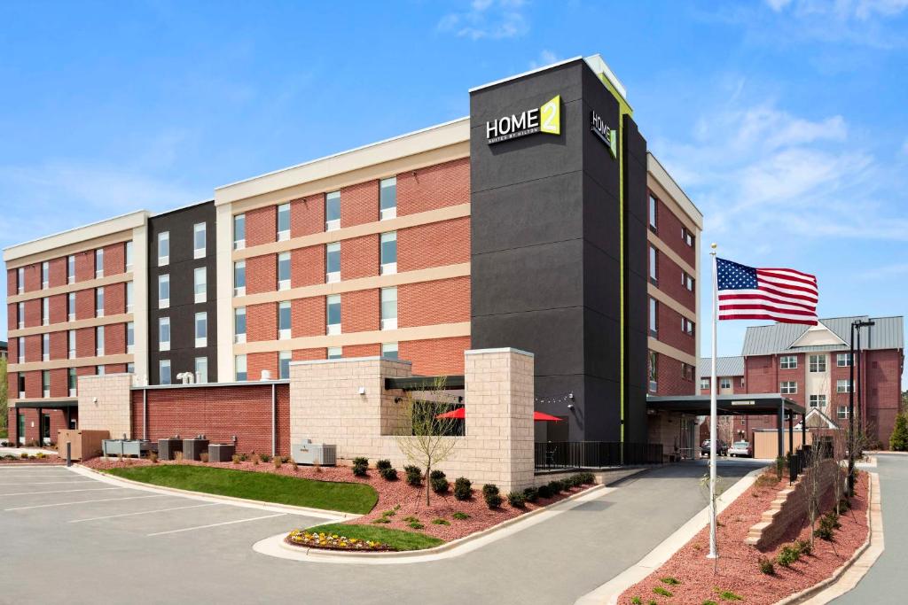 a hotel building with an american flag in front of it at Home2 Suites by Hilton Greensboro Airport, NC in Greensboro