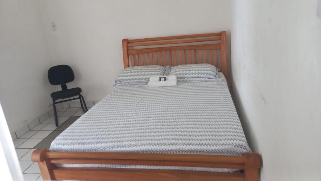 a bed with a wooden frame and a black chair at Hospedaria São Paulo - Quartos com WC Exclusivo in Recife