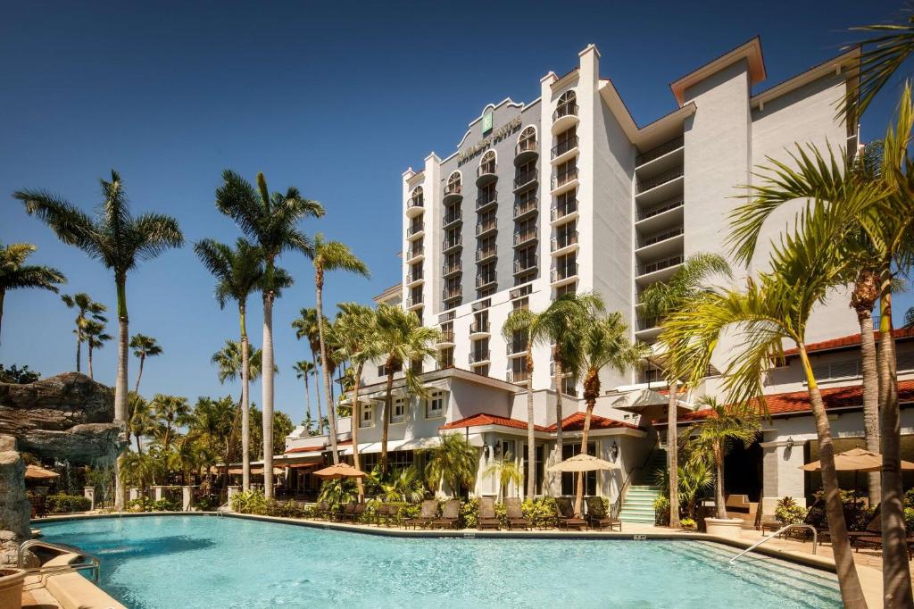 een hotel met een zwembad en palmbomen bij Embassy Suites by Hilton Fort Lauderdale 17th Street in Fort Lauderdale