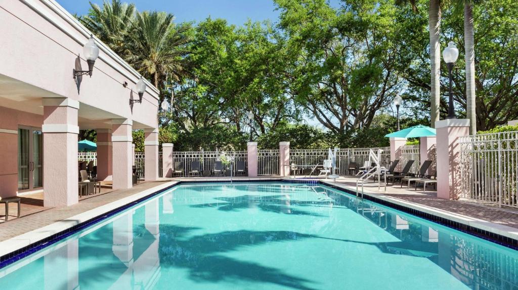 a pool with chairs and umbrellas next to a building at DoubleTree by Hilton Sunrise - Sawgrass Mills in Sunrise