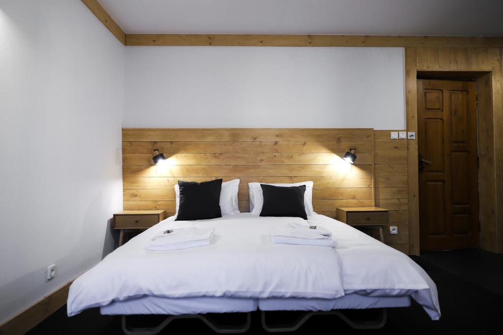 1 dormitorio con 1 cama grande con sábanas y almohadas blancas en Wysoka noclegi ze śniadaniem, en Krynica-Zdrój