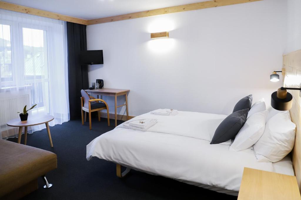 a hotel room with a white bed and a desk at Wysoka noclegi ze śniadaniem in Krynica Zdrój