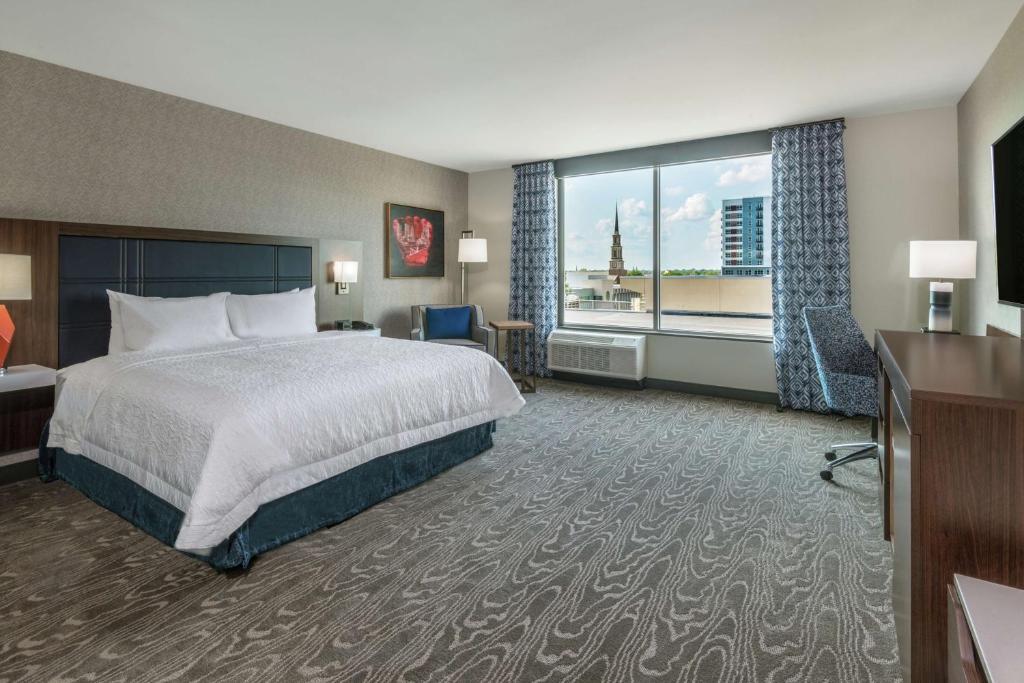 a hotel room with a bed and a large window at Hampton Inn & Suites Fort Wayne Downtown in Fort Wayne