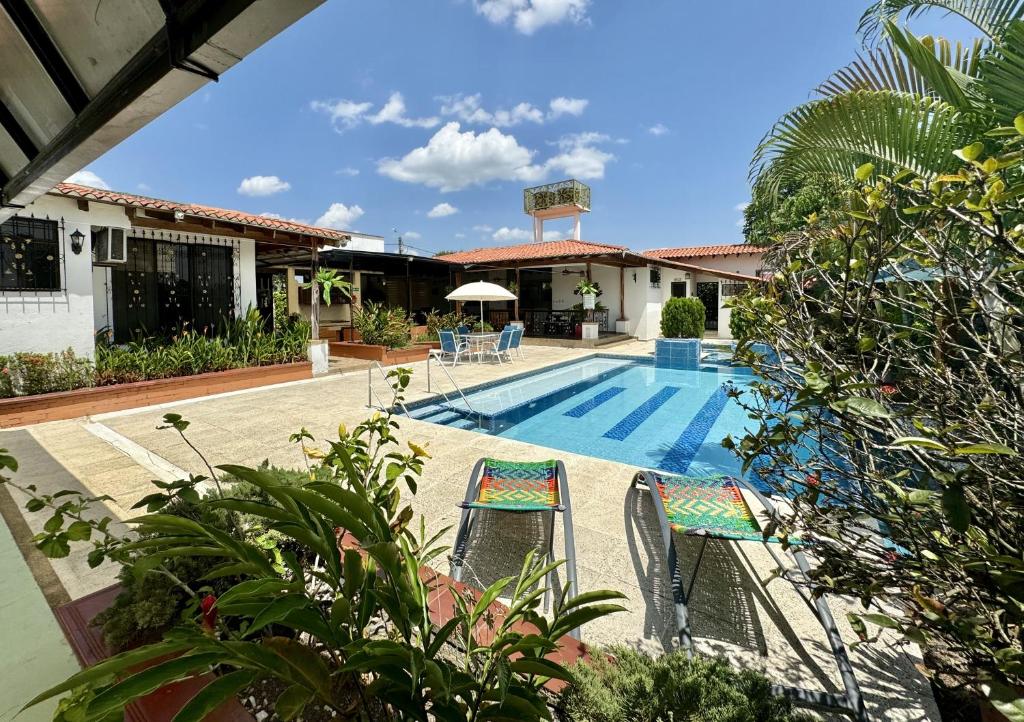 a pool with two chairs next to a house at Cabaña La Betica in Villavicencio