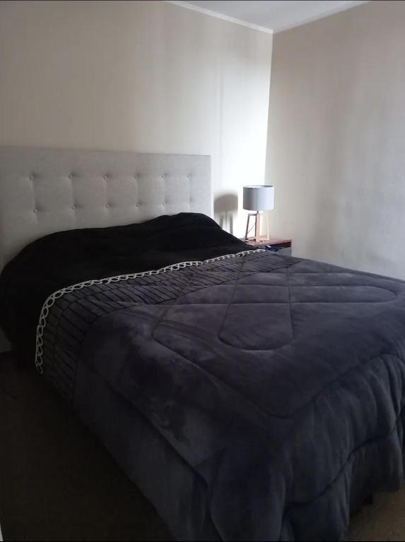 um quarto com uma cama grande e um edredão azul em Departamento por días em Arica