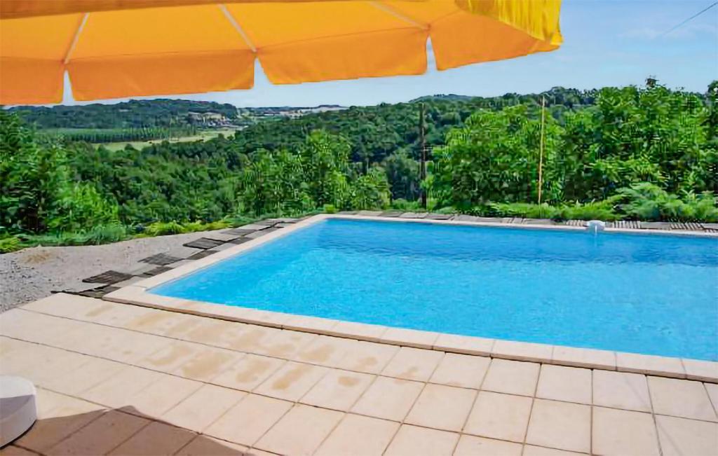 einen Pool mit Sonnenschirm und Blick auf die Bäume in der Unterkunft Cozy Home In Montignac With Kitchenette in Montignac